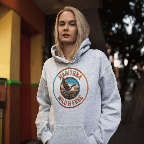Celebrate the heart of the prairies with our Manitoba – Wild & Free hoodie, featuring a stunning graphic of a Canadian goose soaring over golden wheat fields.